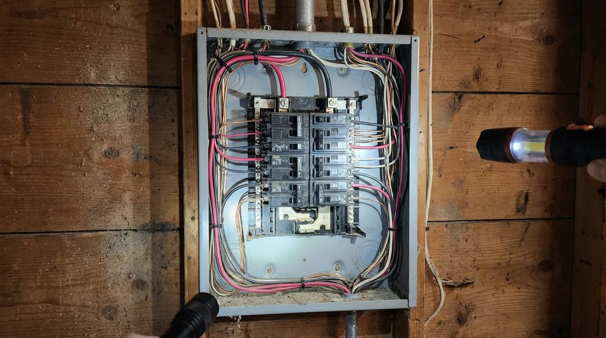Open residential electrical panel with the dead front removed, showing circuit breakers and copper branch wiring during a 4-point inspection